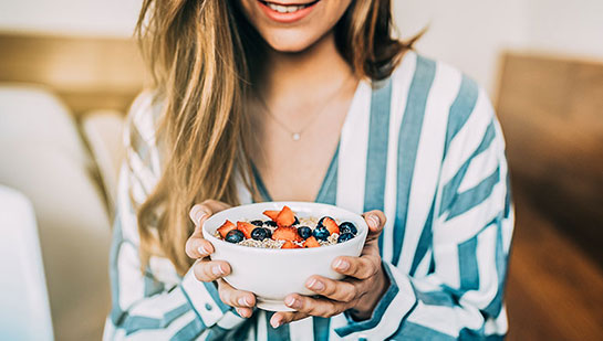 Woman eating a healthy cereal after receiving diet guidance from Cary chiropractor