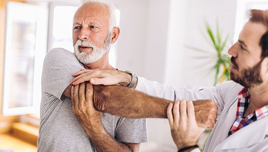 Elderly man receiving shoulder adjustment from Cary chiropractor