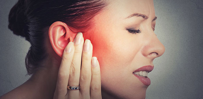 Woman holding her ear in pain due to ear infection before visiting Cary chiropractor