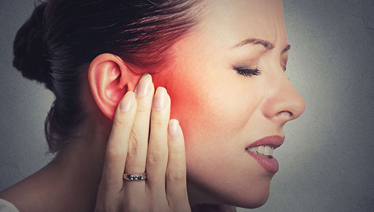 Woman holding her ear in pain due to ear infection before visiting Cary chiropractor
